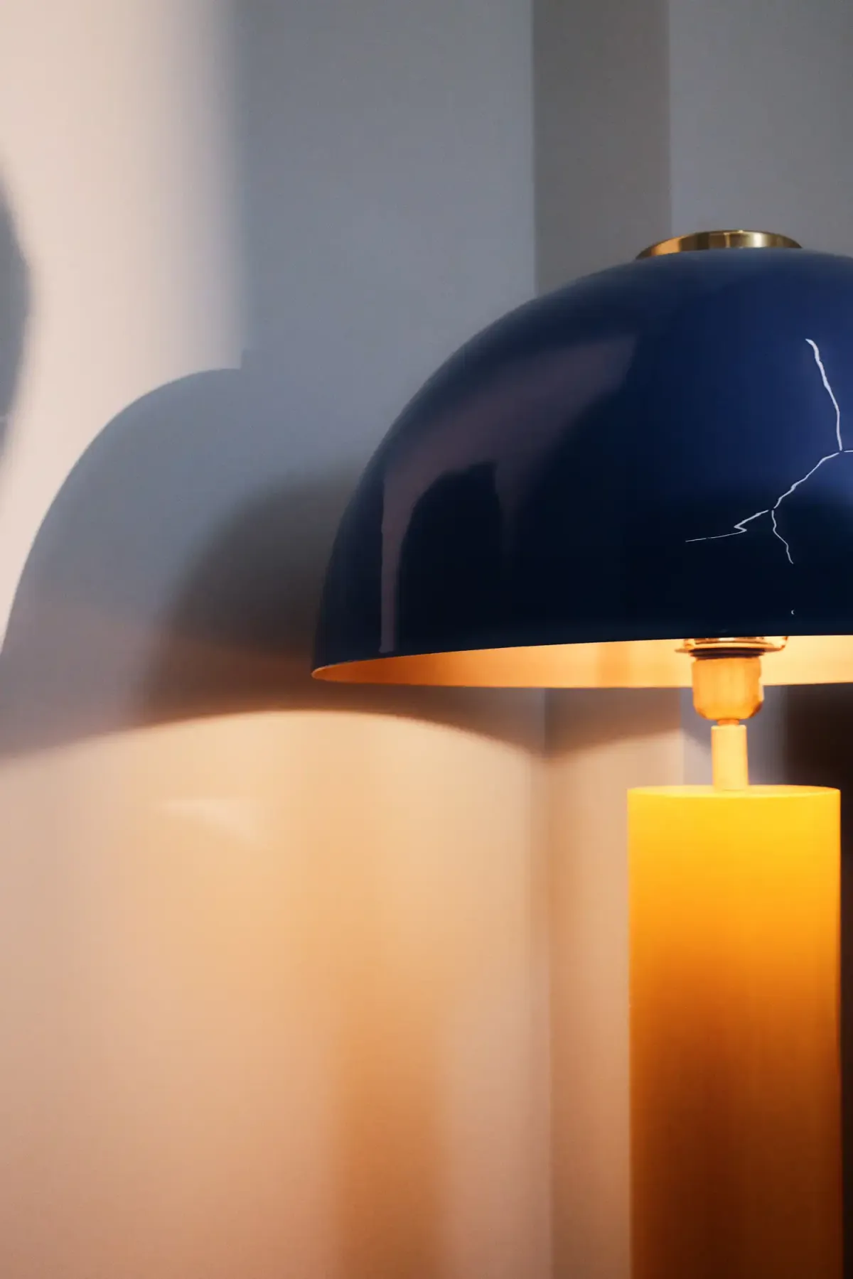 Modern designer lamp with blue shade and yellow base in warm light