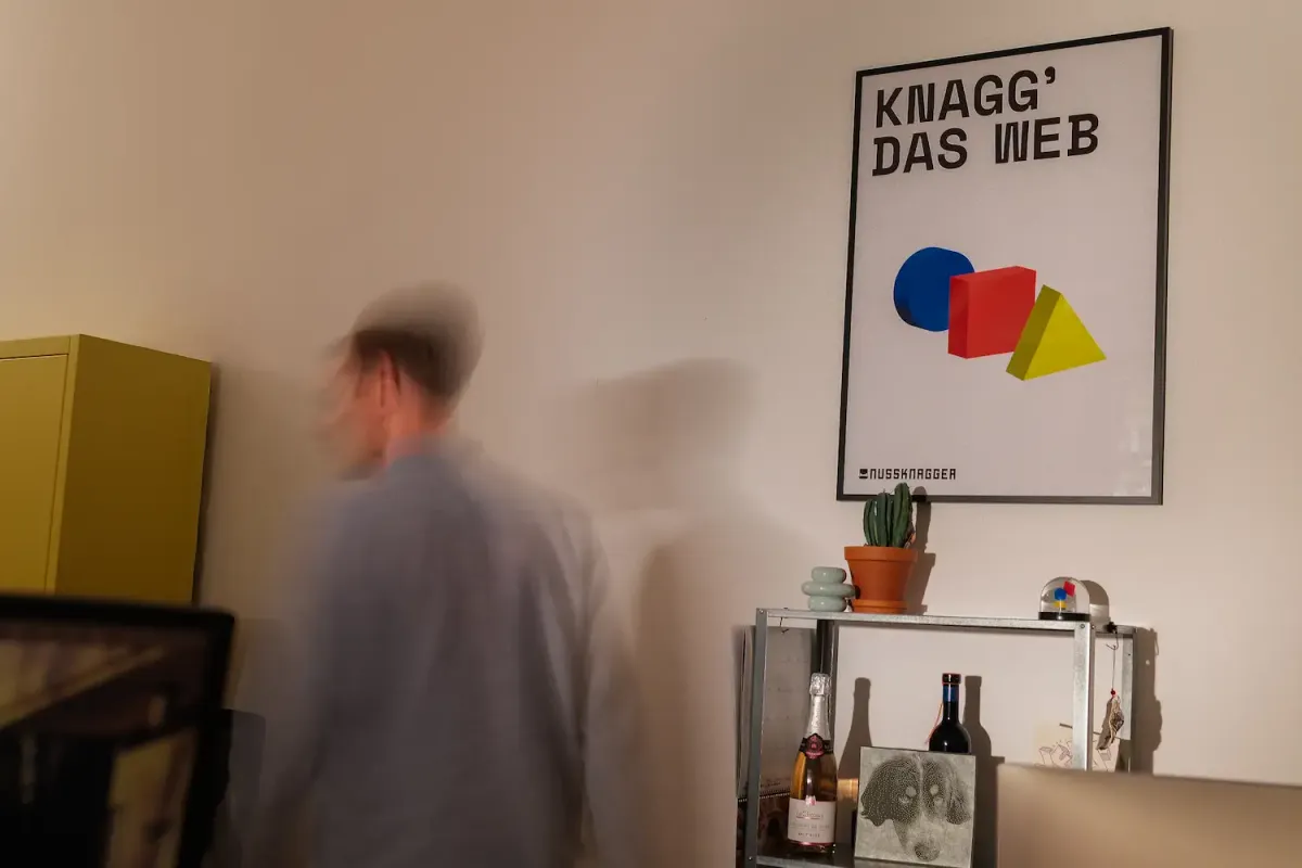 Office space with nussknagger poster 'Knagg the web' and person in motion in front of yellow cupboard